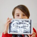歯並びの悪いレントゲン写真を持った子ども
